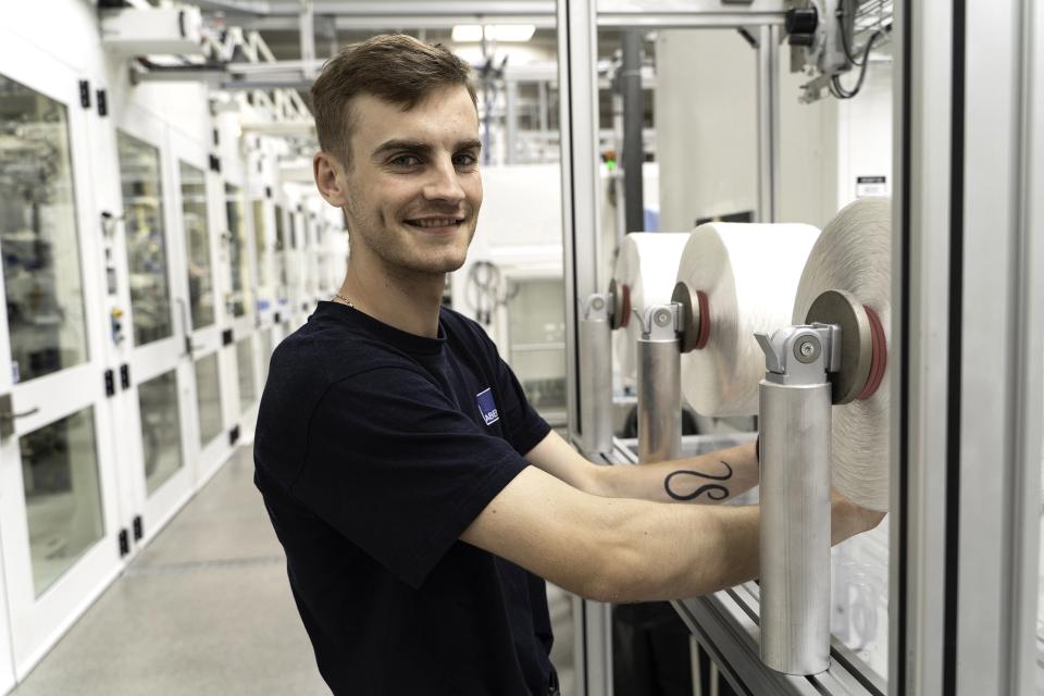 Ung mand, der står med hænderne i ABENAs bleproduktion