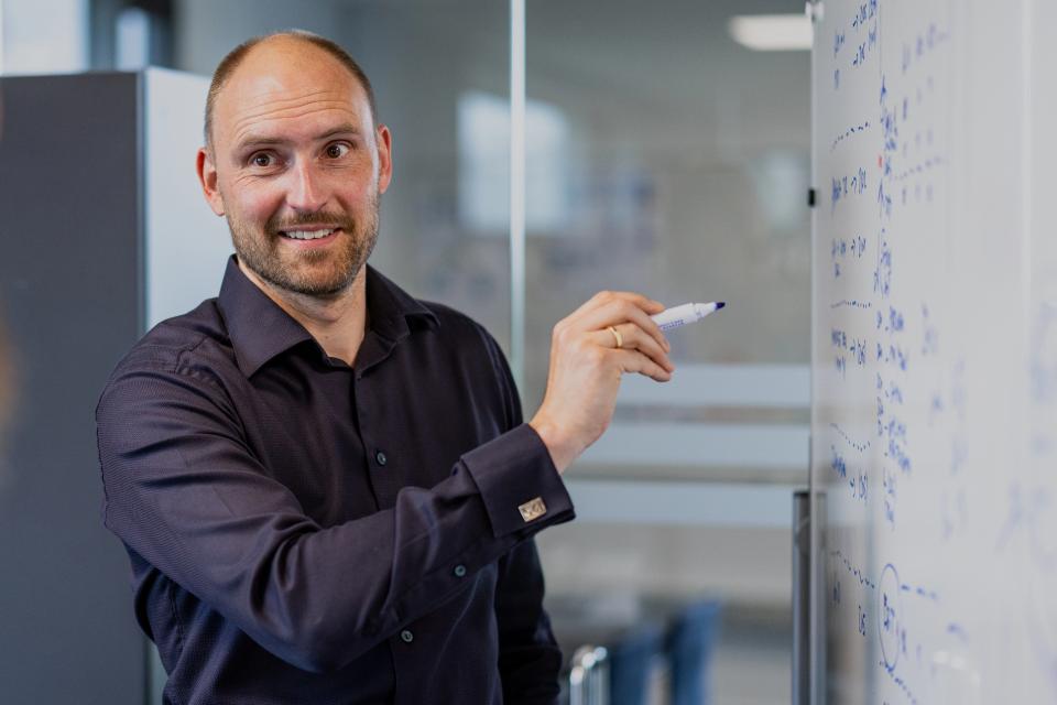 Mand, der står foran tavle, som han skriver på