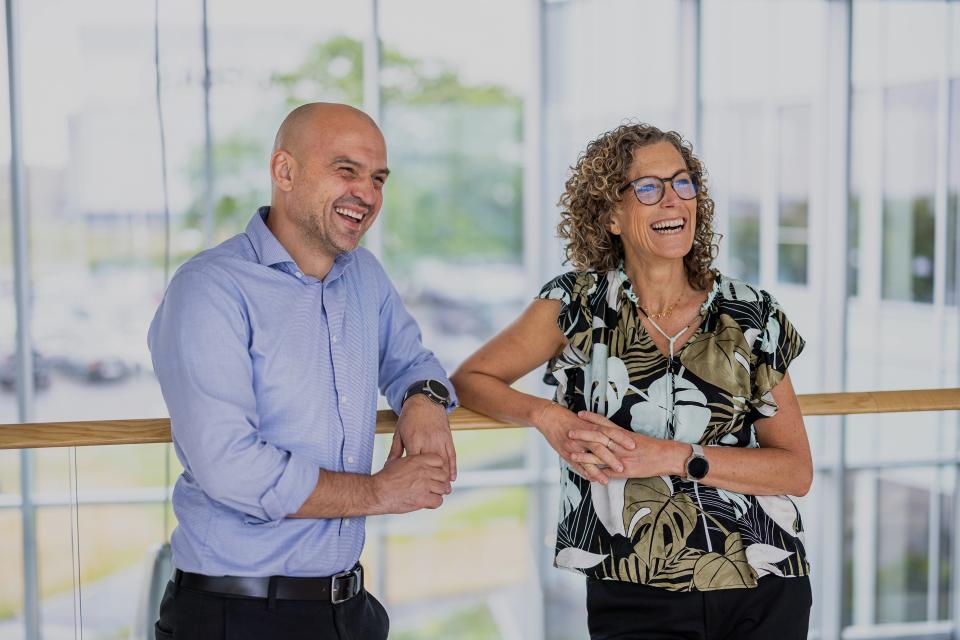 To medarbejdere fra ABENA, der står sammen og griner