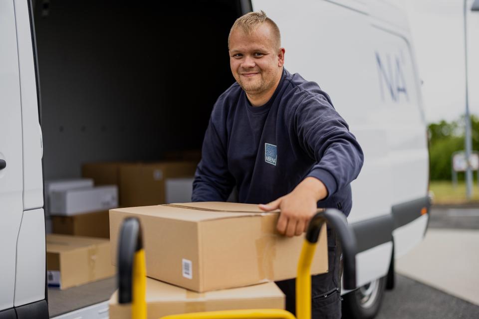 Mand, der pakker en ABENA-bil med pakker