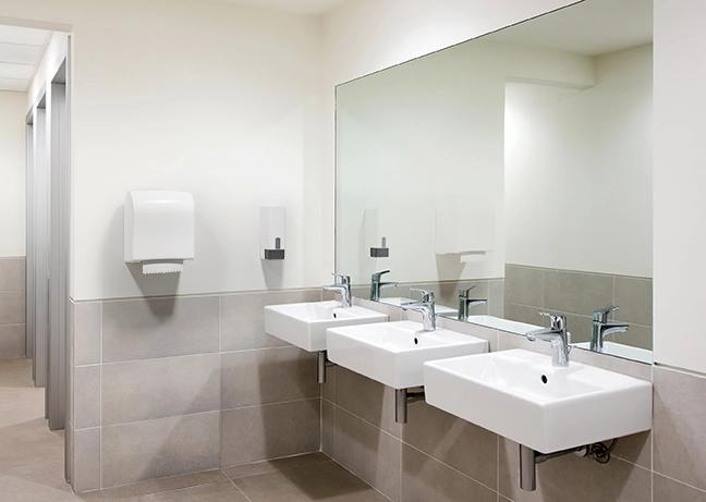 Badeværelsesmiljø med dispenser til papir og sæbe på væggen