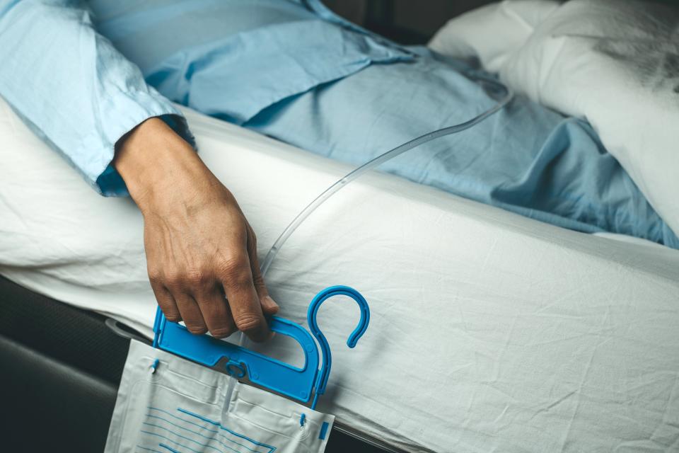 Patient, der ligger i sengen med et kateter og en urinpose