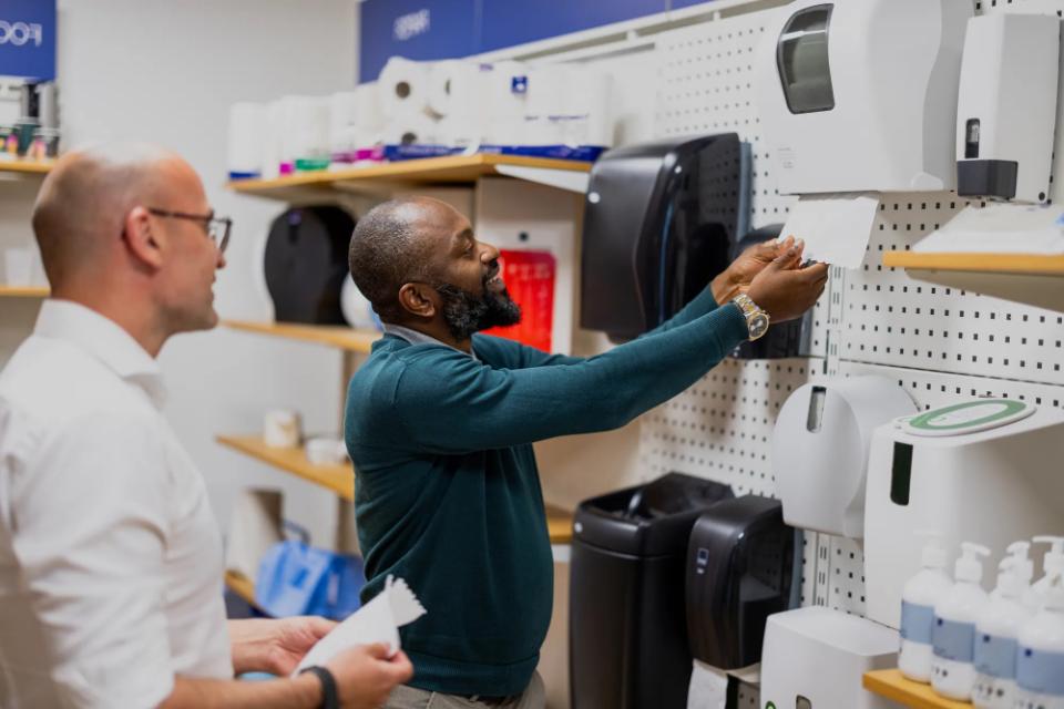 En medarbejder demonstrerer, hvordan man bruger en papirdispenser