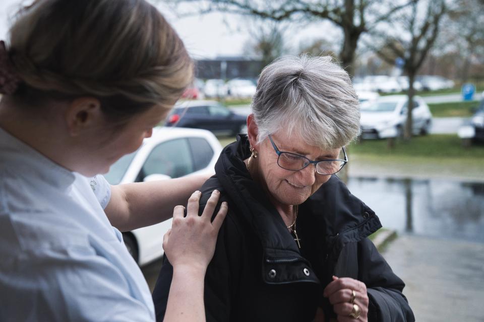 Plejepersonale, der holder ældre borger på skulderen udenfor